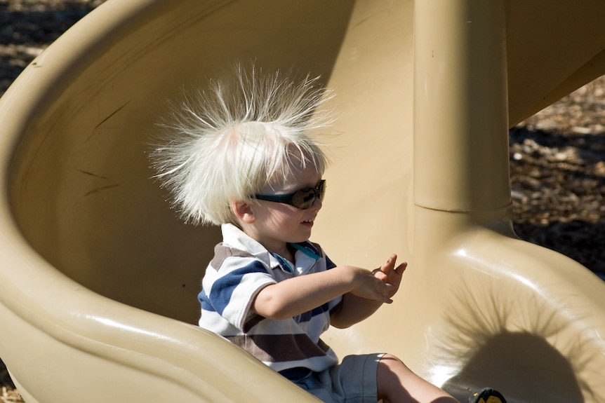 A young child on a slide is stuck in her hair.